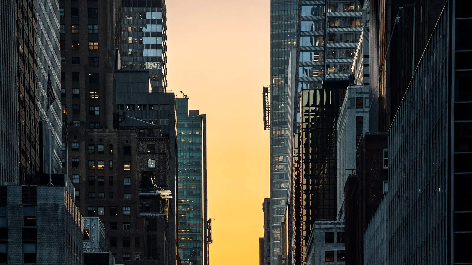 Cars filling a city avenue at sunset with the sun low between the buildings.